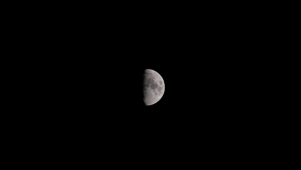 a half moon is seen in the dark sky