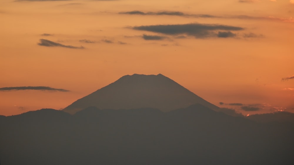 the sun is setting behind a mountain in the distance