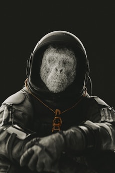 A figure in a dark astronaut suit with a helmet and an abstract, wire-like structure forms the face. The scene is dimly lit, creating a mysterious and futuristic atmosphere.