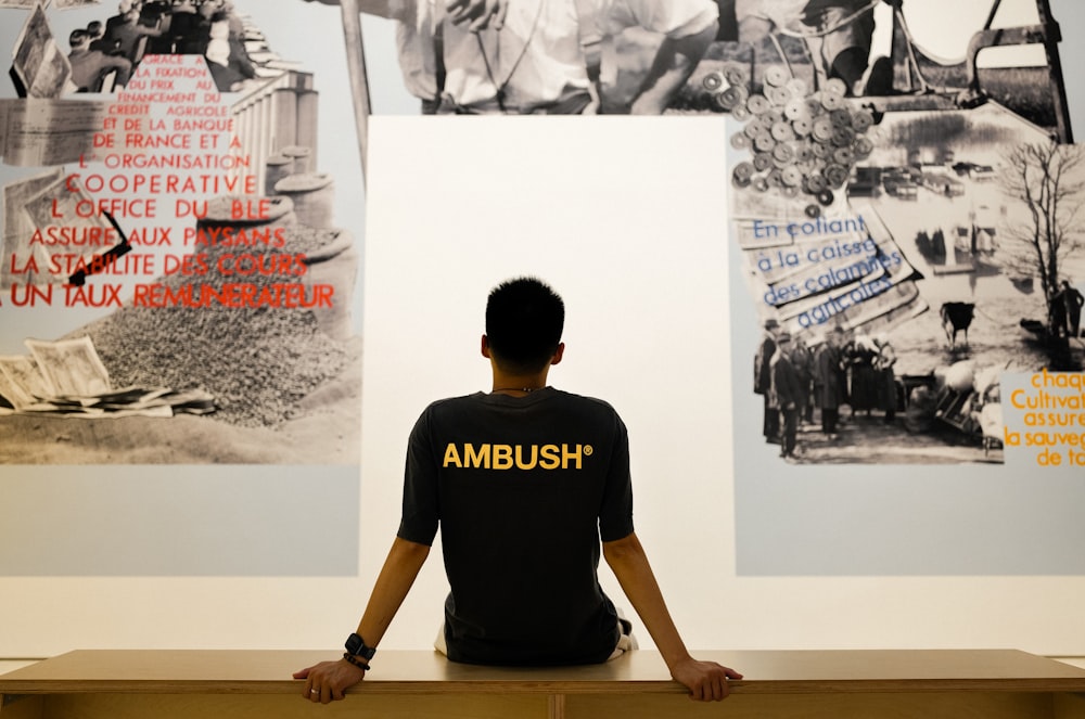 a man sitting in front of a wall with pictures on it