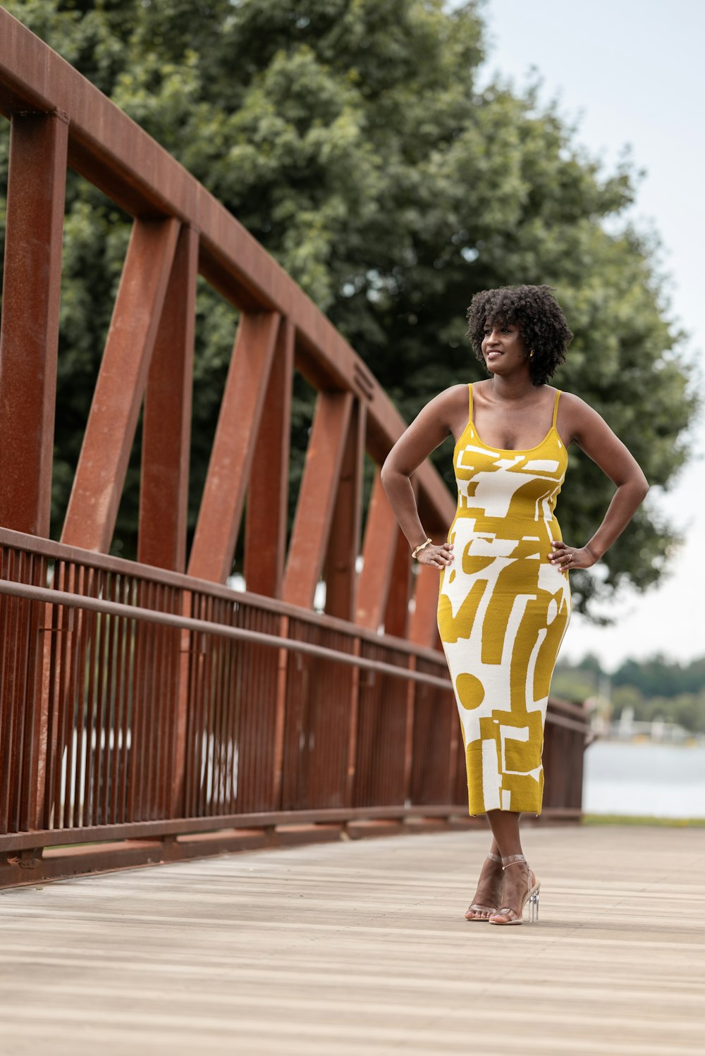 a woman in a yellow dress standing on a bridge