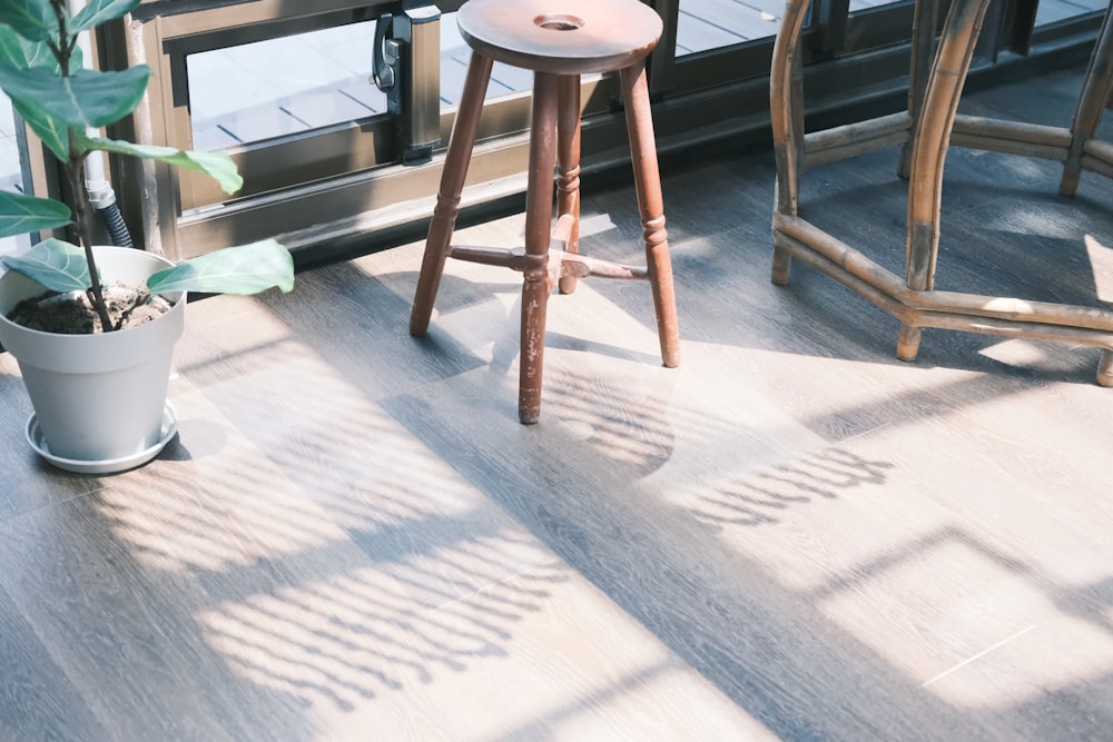 a wooden stool sitting next to a potted plant