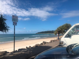 A calm beach scene with a car parked safely and friends enjoying the shore responsibly.