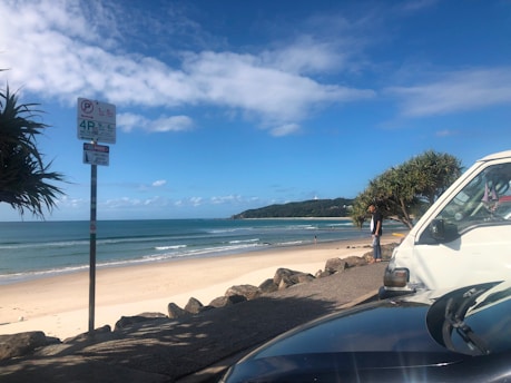 A calm beach scene with a car parked safely and friends enjoying the shore responsibly.