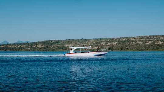 A beautiful speedboat cruising near lush green islands under a bright blue sky in Camamu Bay.