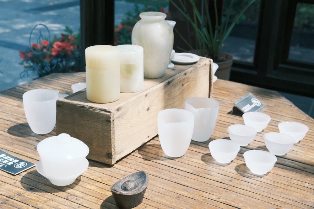 a wooden table topped with lots of white cups