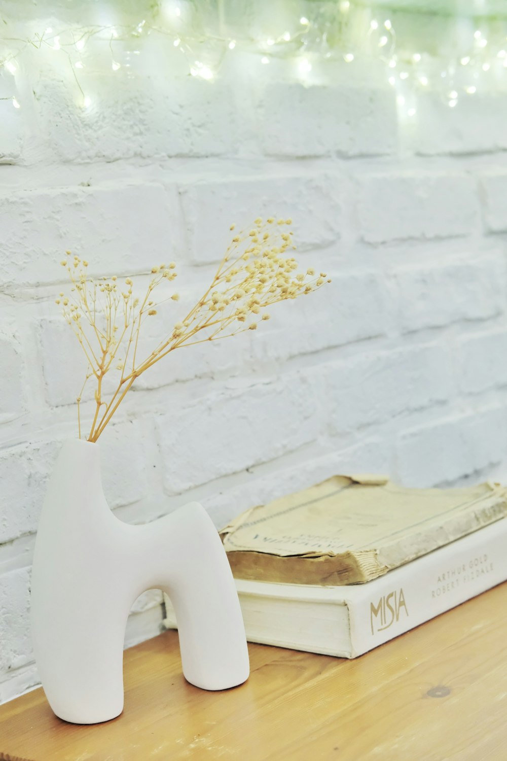 a white vase with a plant in it sitting on a table