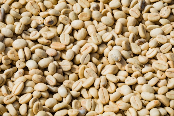 A close-up of raw coffee beans spread out on a burlap sack.