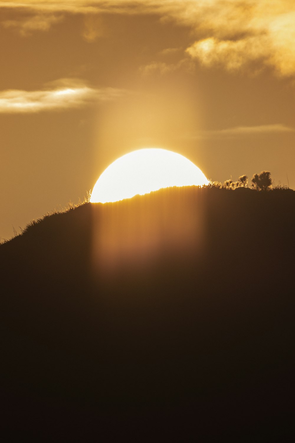 the sun is setting over a hill with a horse in the foreground