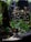 An aquarium scene featuring lush green aquatic plants and small orange fish swimming among the foliage. The base of the aquarium is lined with dark rocks and sandy substrate. The plants provide a dense, natural look with varying shades of green and hints of red.