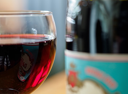 A close-up of a wine bottle and glass, highlighting the rich color of the wine.