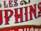 Close-up view of stylized text with bold, vivid red and blue letters outlined in black against a beige textured background. The design includes ornamental scrolls in gold, adding a vintage or classic feel.
