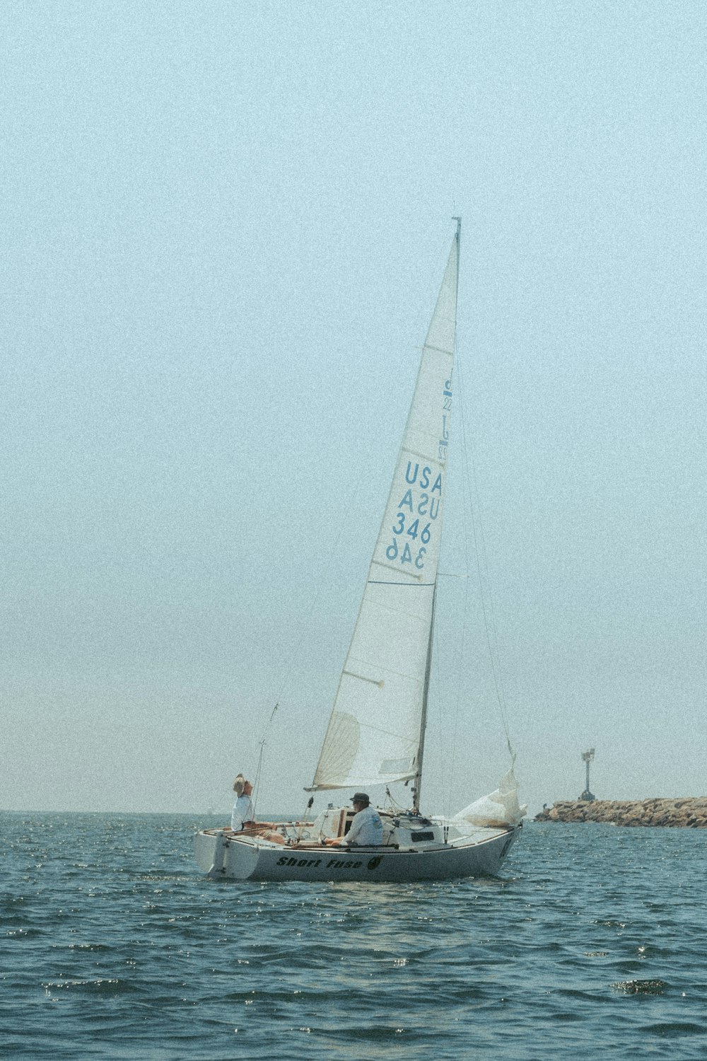 a sailboat with a white sail is in the water