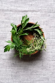 a wooden bowl filled with herbs on top of a table