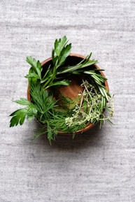 a wooden bowl filled with herbs on top of a table