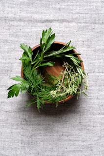 A colorful bowl of fresh vegetables and herbs on a wooden table.