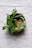 A rustic wooden bowl filled with golden clarified butter surrounded by fresh green herbs on a kitchen counter.