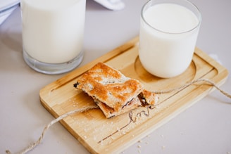 a glass of milk and a piece of toast on a cutting board