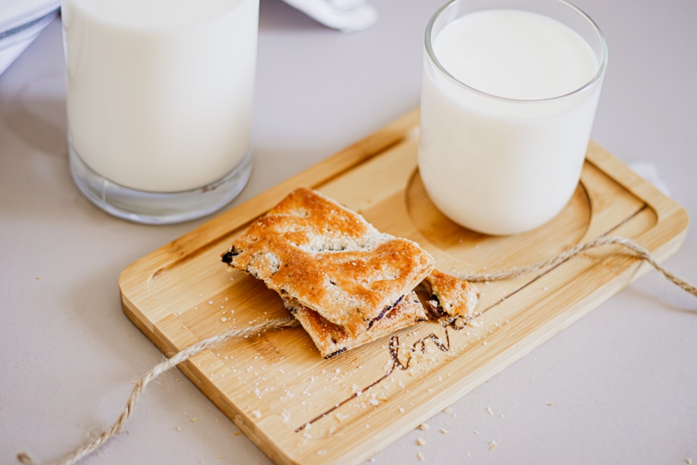 a glass of milk and a piece of toast on a cutting board