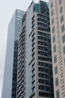 A cluster of modern high-rise buildings with glass and concrete facades. The architecture showcases a sleek and contemporary design, featuring numerous windows and balconies. The buildings are positioned closely together and create an urban cityscape.