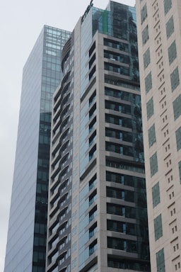 A cluster of modern high-rise buildings with glass and concrete facades. The architecture showcases a sleek and contemporary design, featuring numerous windows and balconies. The buildings are positioned closely together and create an urban cityscape.