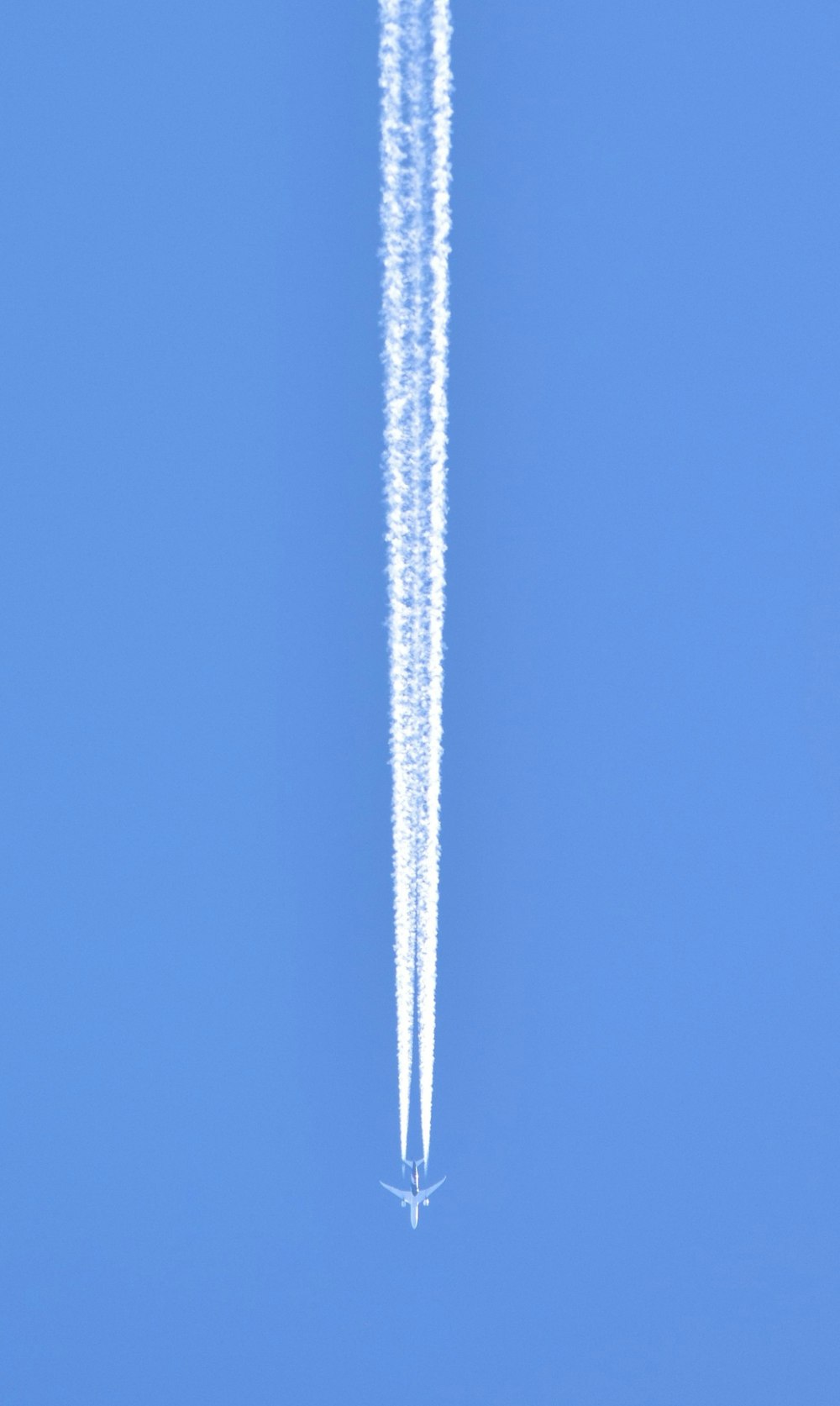 a jet flying through a blue sky leaving a trail of smoke