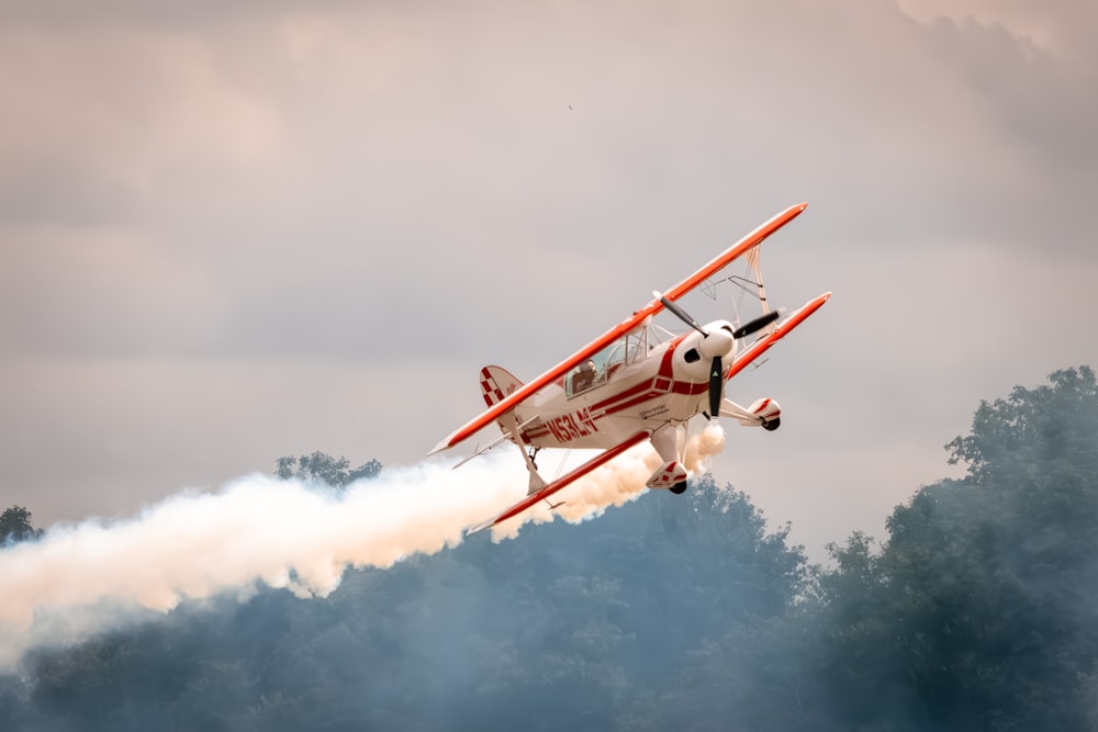 a red and white plane flying over a forest