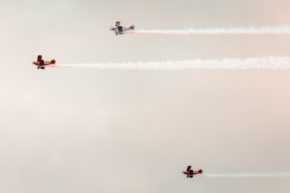 two airplanes flying in the sky with smoke trailing behind them