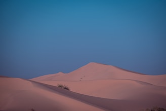 A peaceful scene of rolling desert dunes under a bright blue sky.