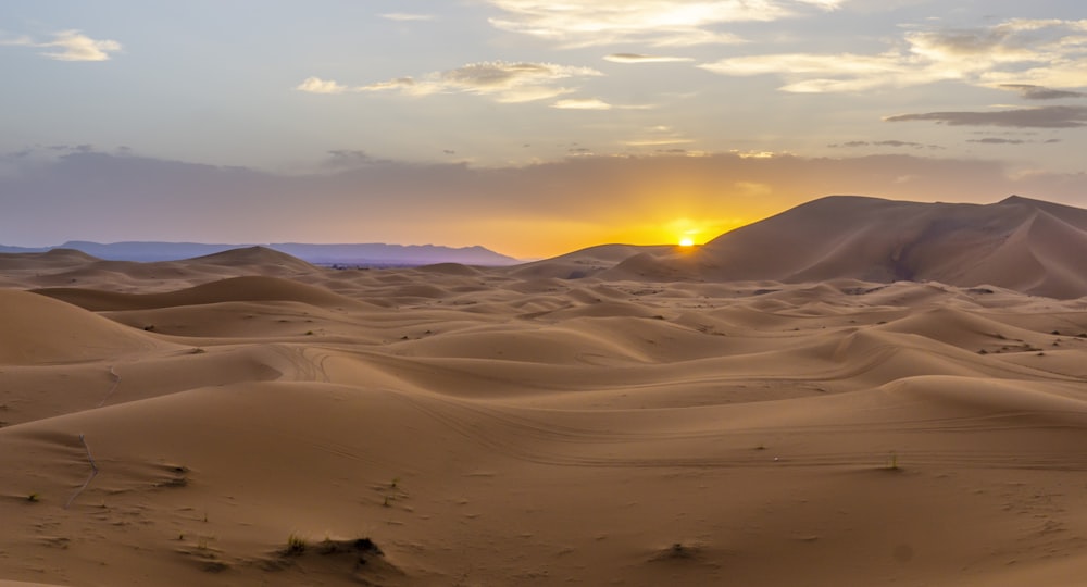 the sun is setting over a desert landscape