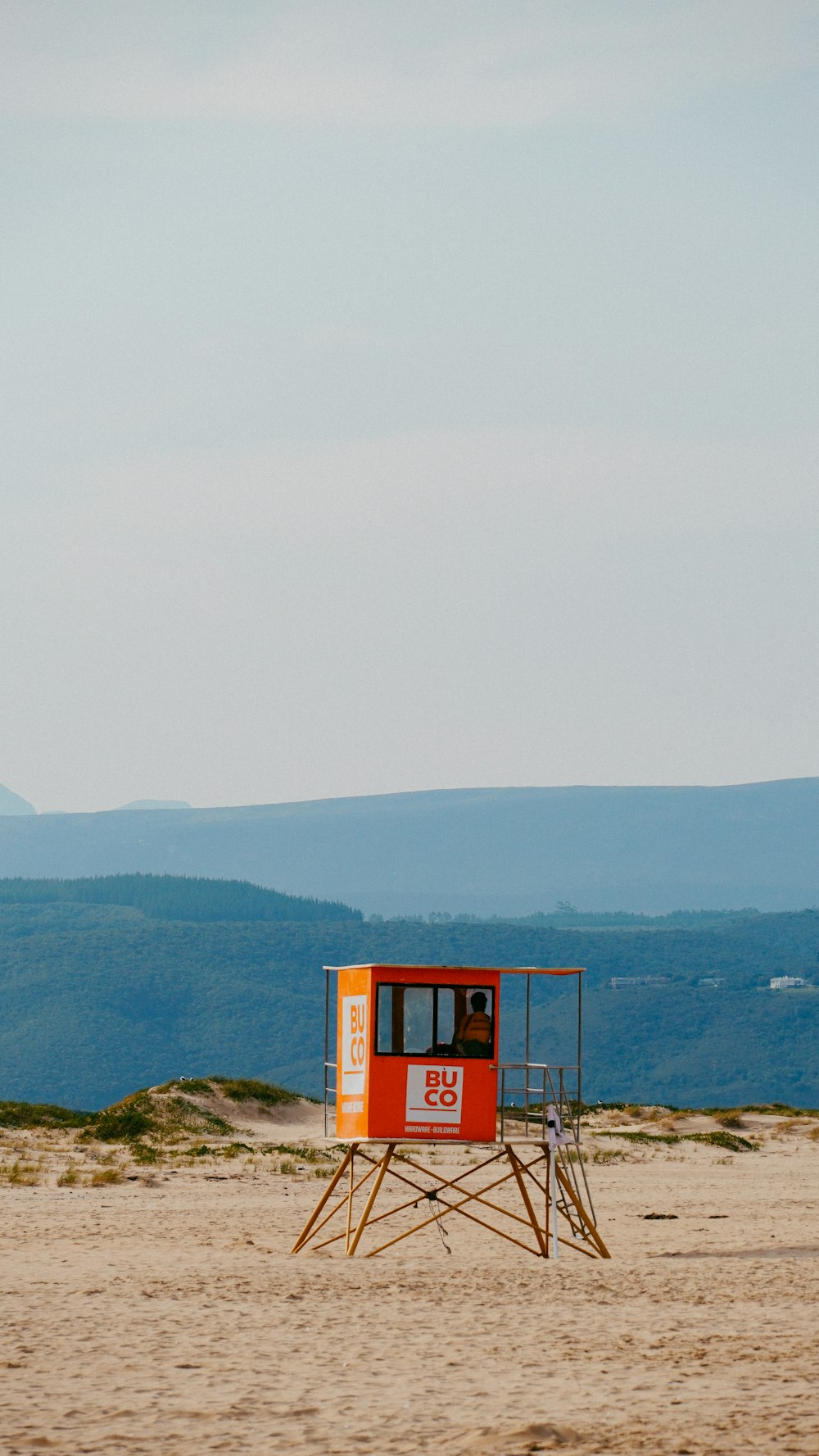 a lifeguard stand on a beach with mountains in the background