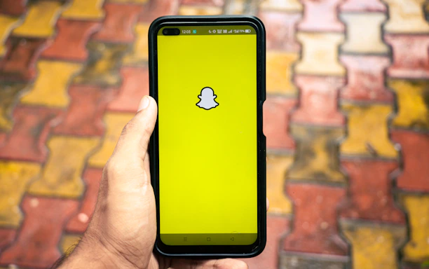 Close-up of a hand scrolling through a list of Snapchat usernames on a phone screen.