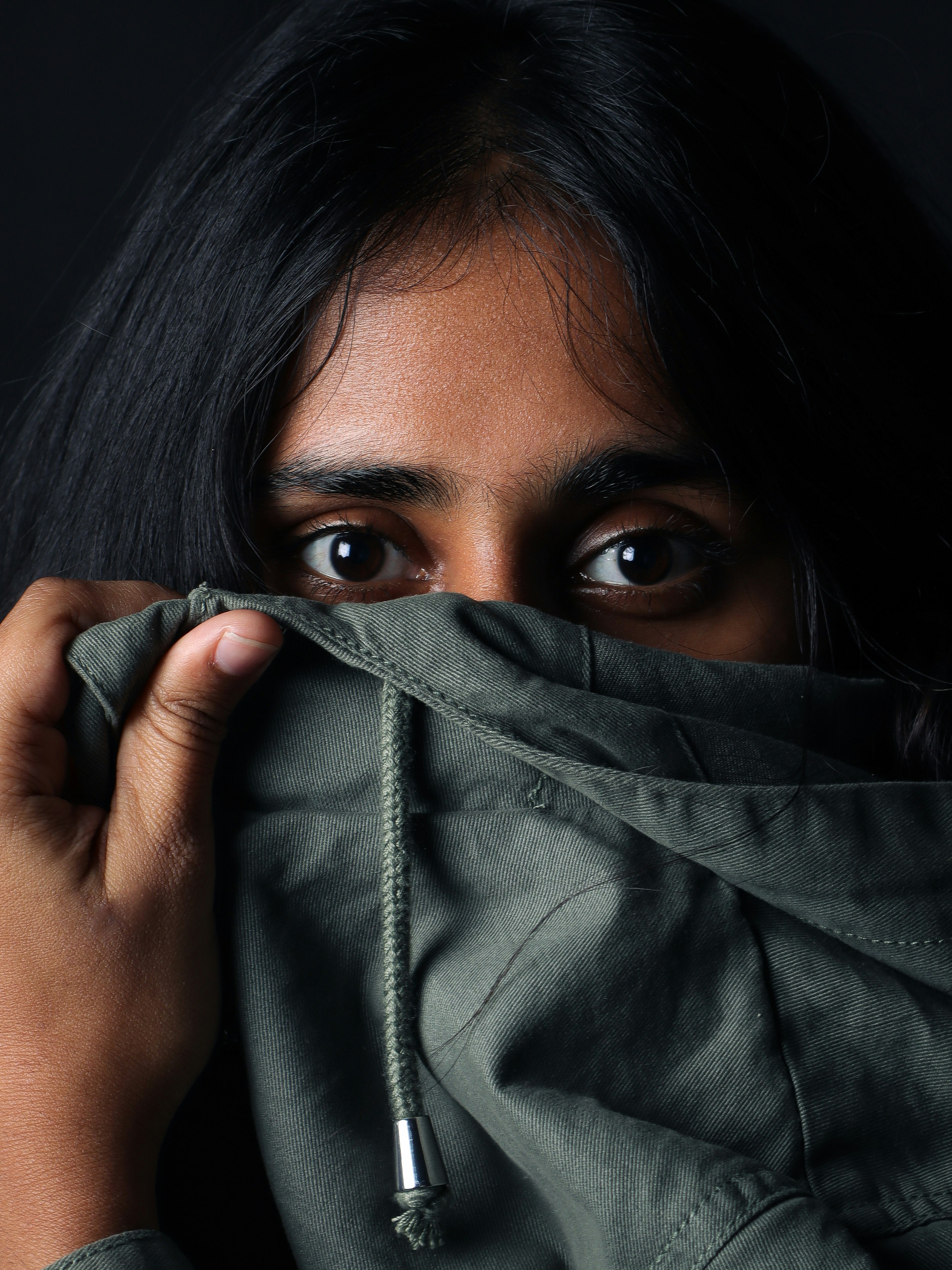 a woman covering her face with a hoodie