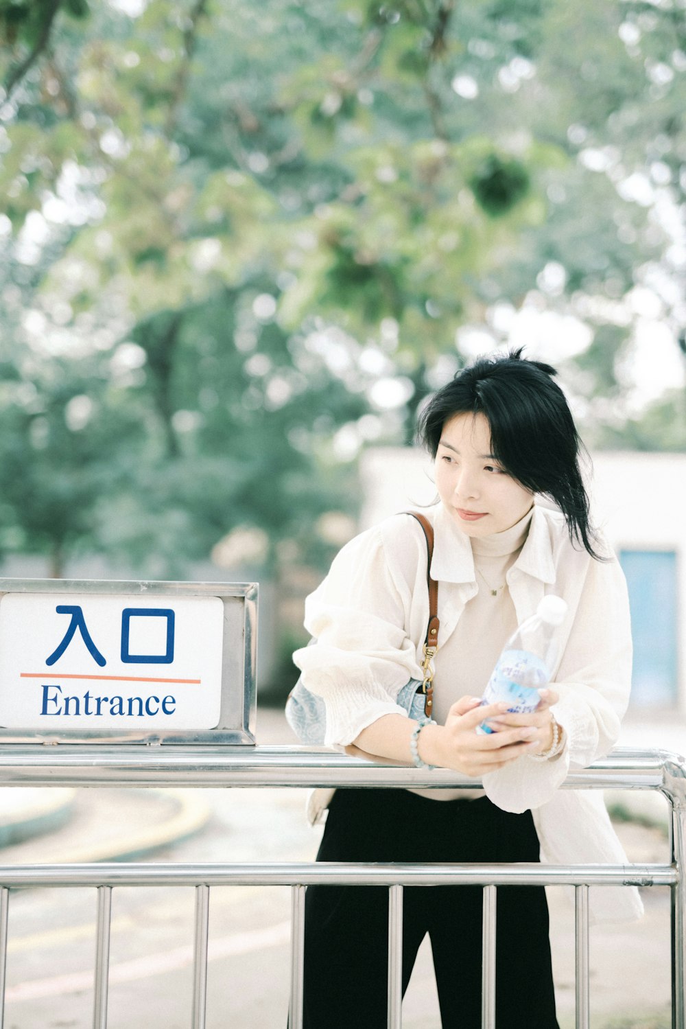 a woman standing next to a fence holding a cell phone