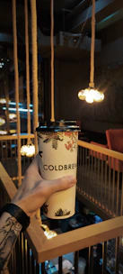 A client enjoying a cup of specialty coffee while the tattoo artist prepares the equipment.