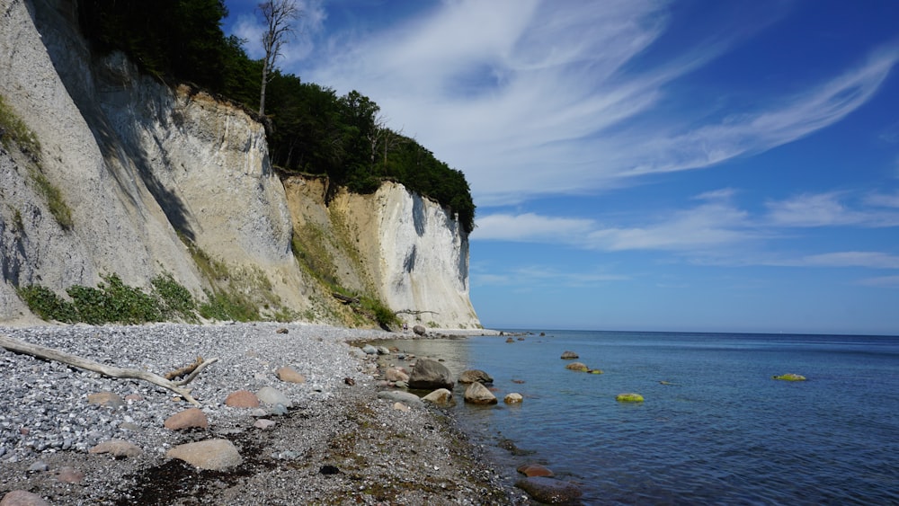 a rocky beach next to a cliff on a sunny day