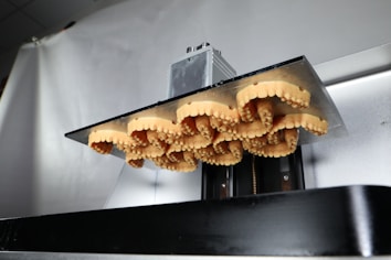 A close-up view of several dental molds aligned and held in place by a metal apparatus. The molds display detailed tooth imprints, suggesting they are used for dental purposes. The setting appears to be industrial or clinical, focusing on precision and functionality.