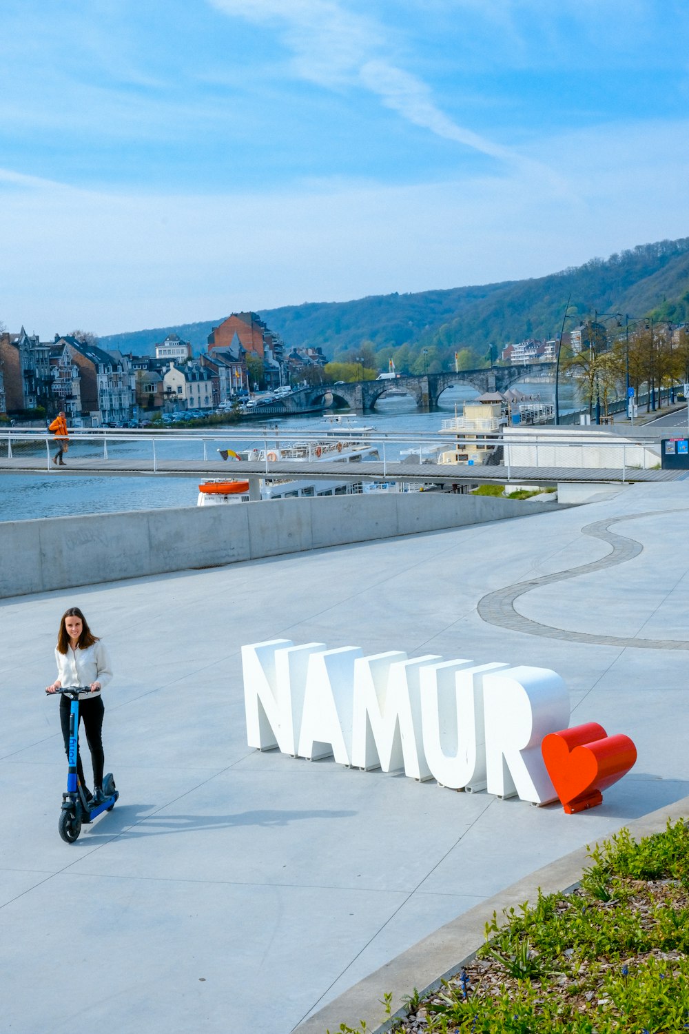 a woman riding a scooter next to a sign