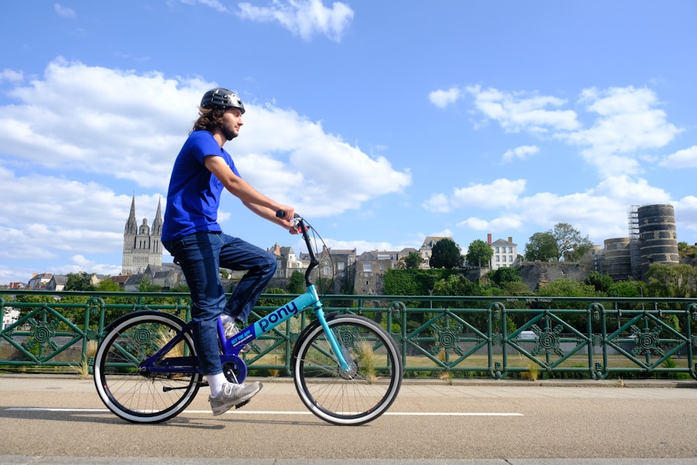a man riding a blue bike across a bridge
