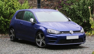 A clean, freshly washed blue hatchback parked near the wcars service area.