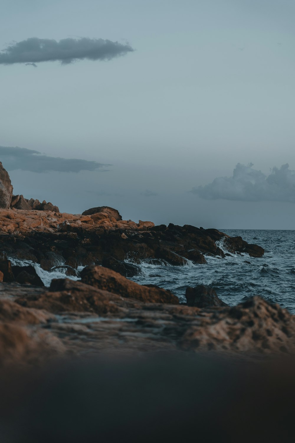 a person standing on a rocky shore next to the ocean