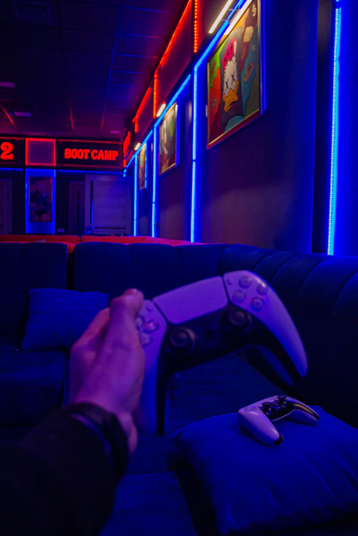Close-up of a gamer holding a glowing game controller in a dark room with neon lights