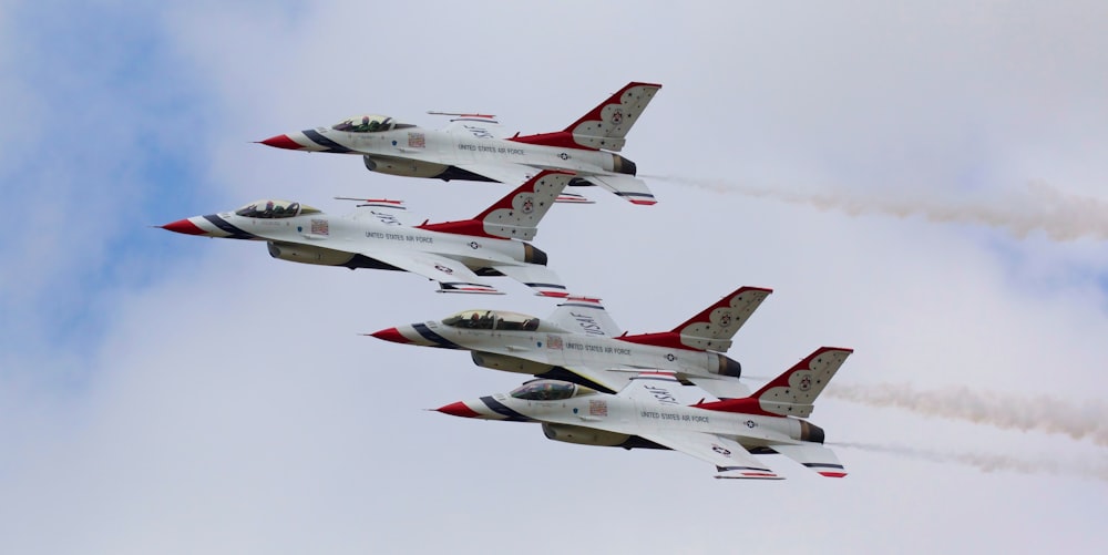 a group of fighter jets flying through a cloudy sky