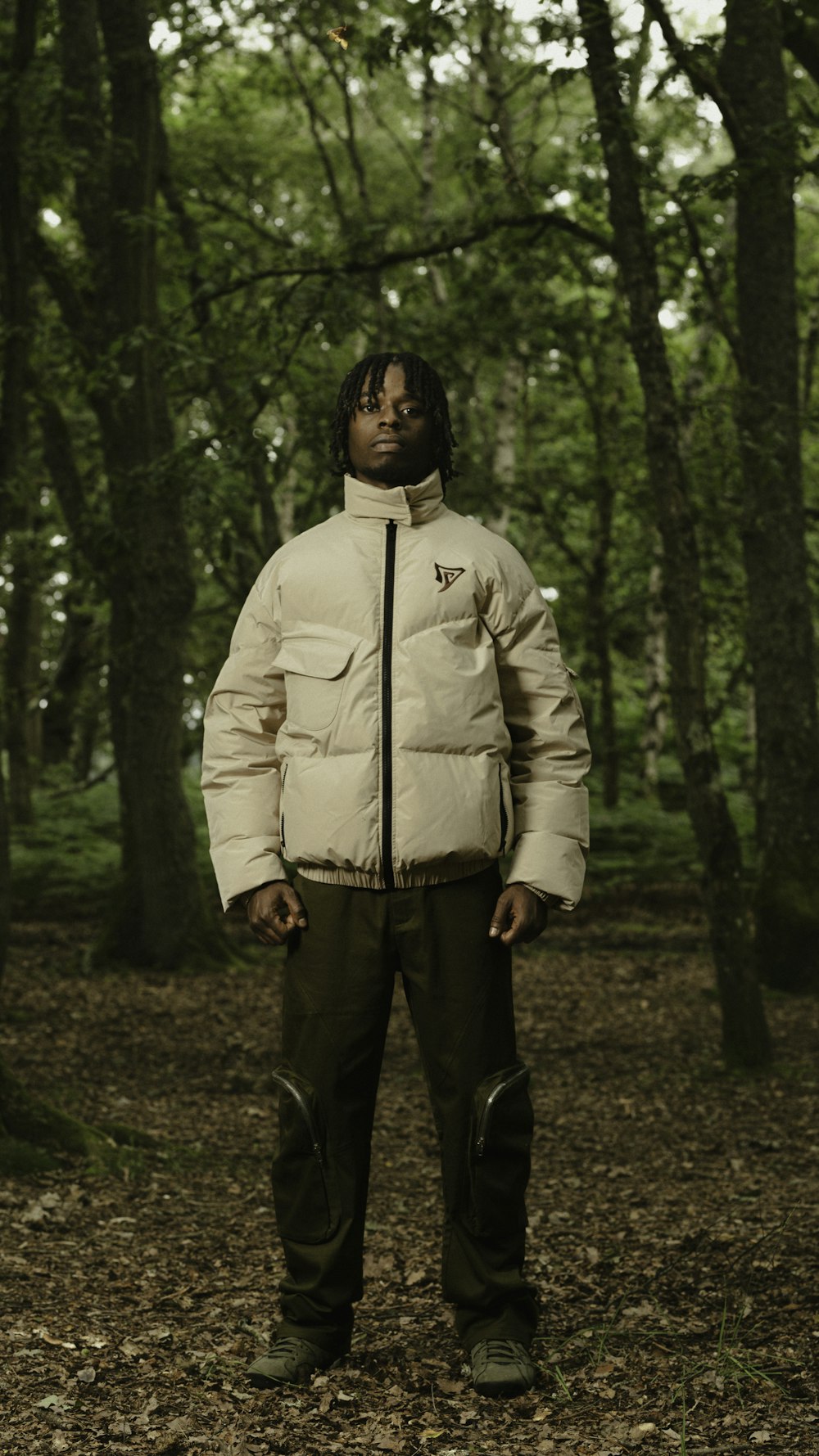 a man standing in the woods wearing a jacket