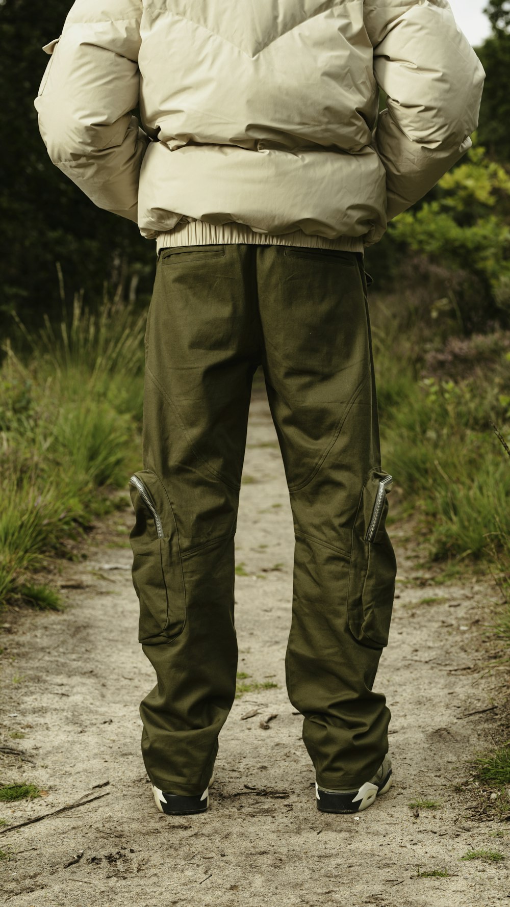 a man standing on a dirt road with his back to the camera