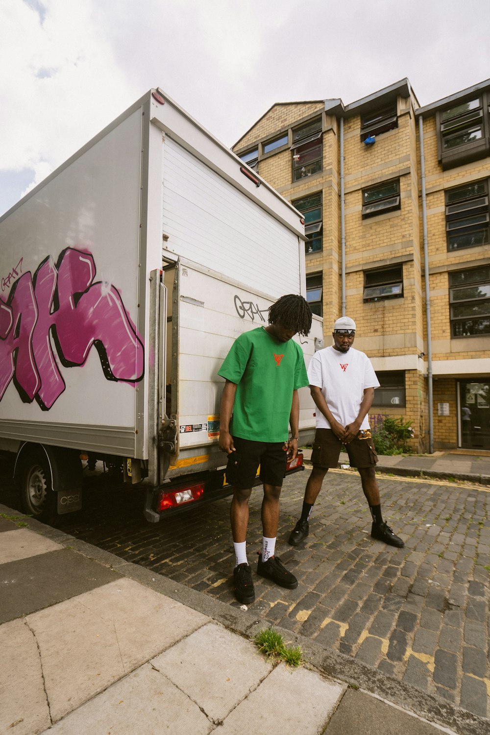 two men standing next to a truck with graffiti on it