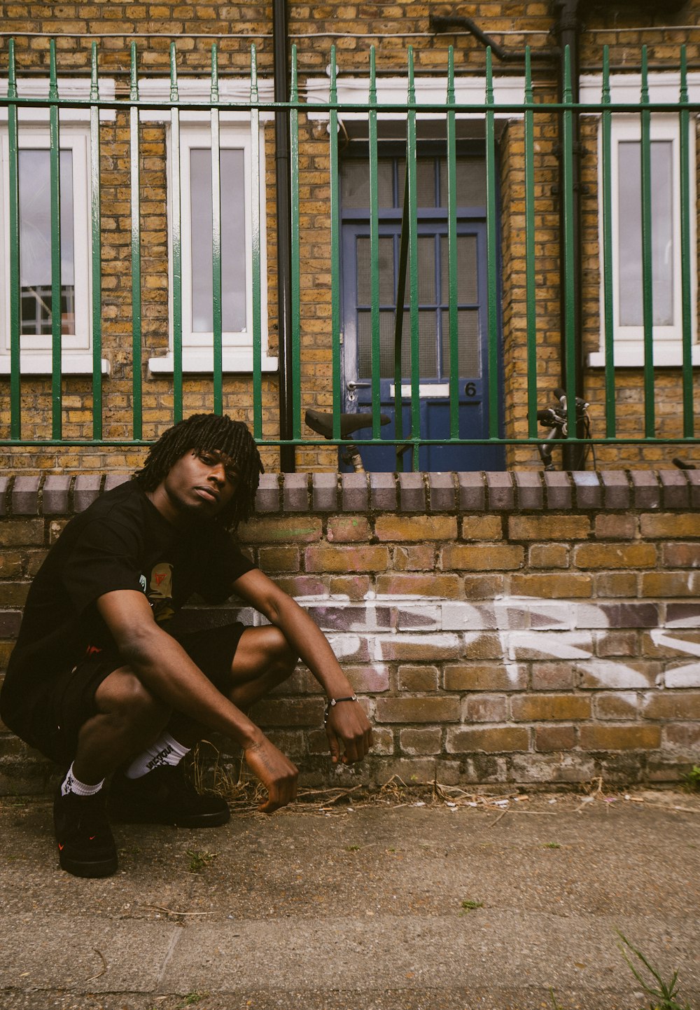 a man sitting on the ground next to a brick building