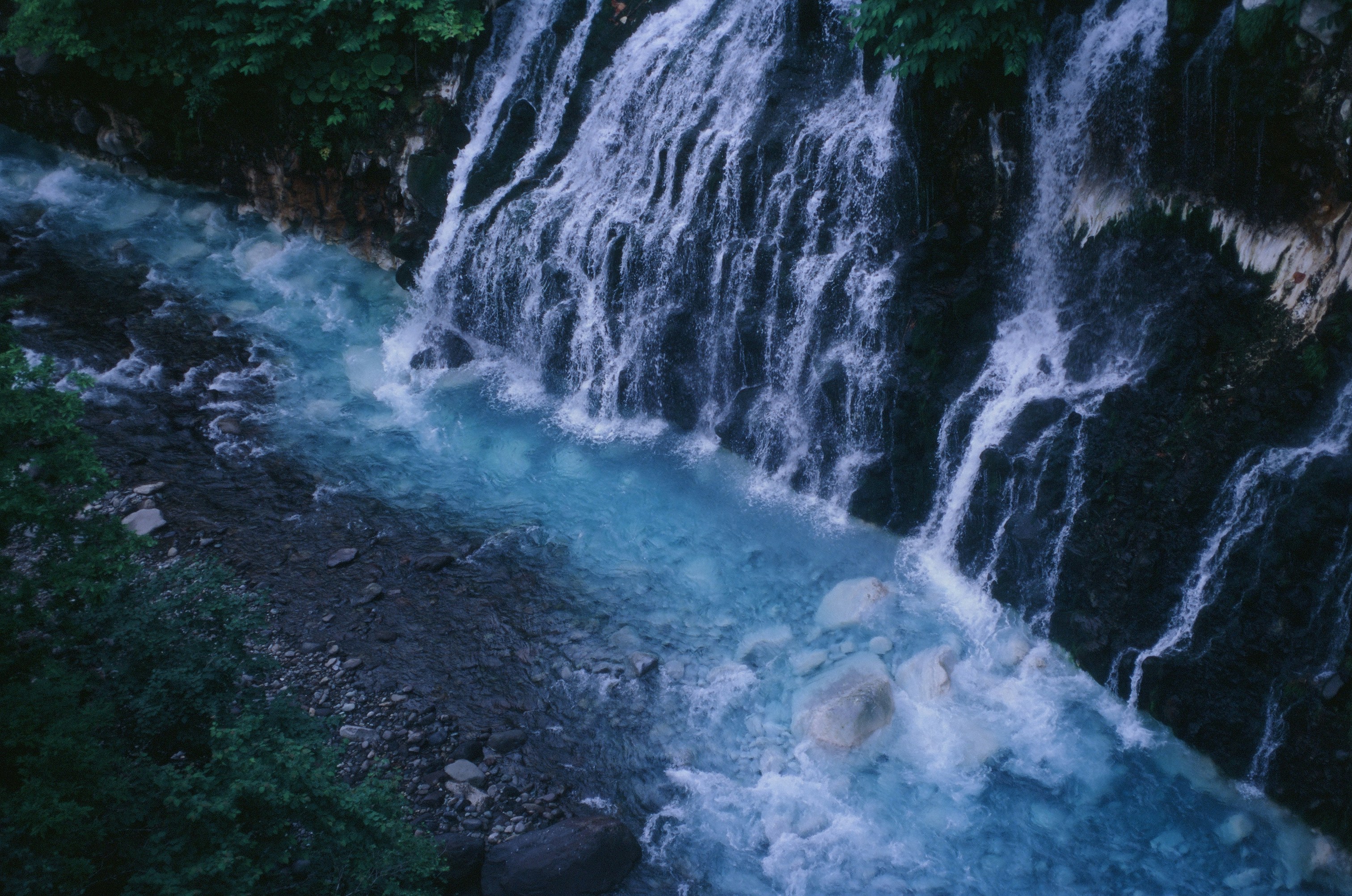 a waterfall with blue water running down it, 