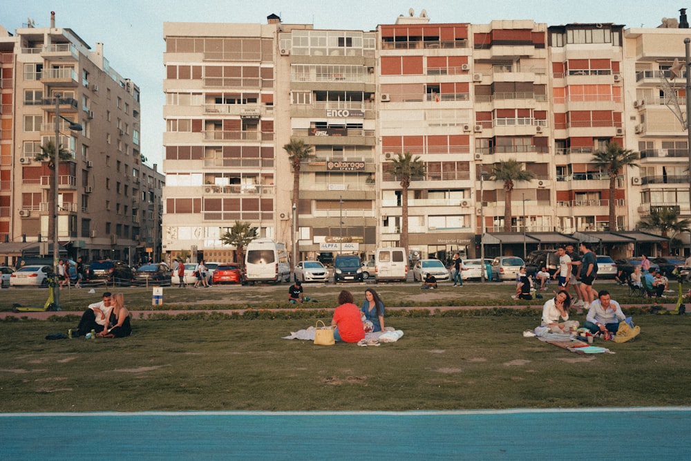 a group of people sitting on the grass in front of a building