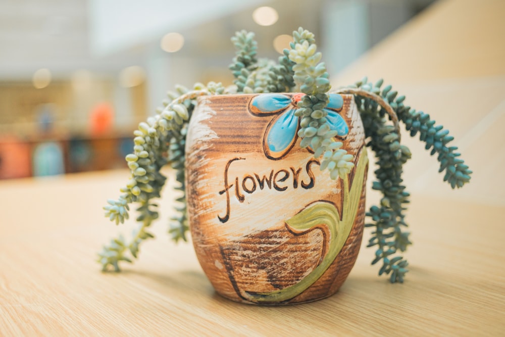 a planter with flowers painted on it sitting on a table